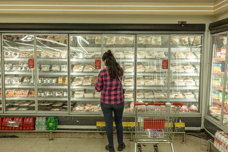 Mujer eligiendo precios de carne en un supermercado Mujer eligiendo precios de carne en un supermercado
