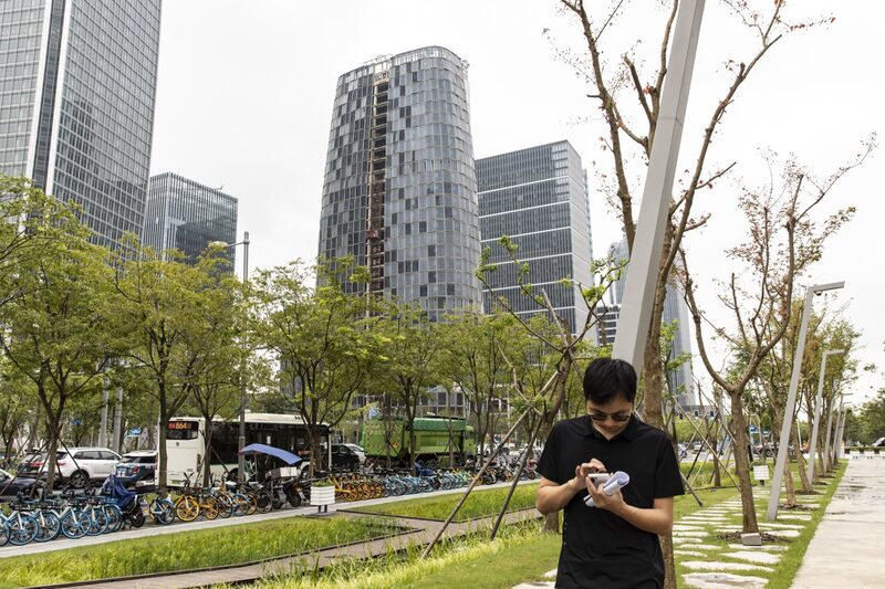 Jovem usa o smartphone enquanto caminha nas proximidades da sede da Tencent Technologies, em Xangai Jovem usa o smartphone enquanto caminha nas proximidades da sede da Tencent Technologies, em Xangai