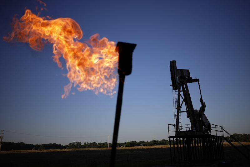 Una antorcha utilizada para la quema de gas asociado ilumina un campo petrolero con una bomba de extracción al fondo. Una antorcha utilizada para la quema de gas asociado ilumina un campo petrolero con una bomba de extracción al fondo.