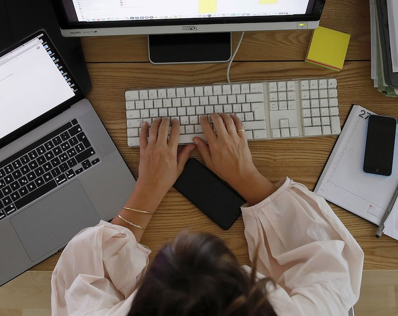 Una mujer trabaja en una computadora de sobremesa junto a un portátil de Apple Inc. en una oficina doméstica en esta fotografía arreglada tomada en Berna, Suiza. Una mujer trabaja en una computadora de sobremesa junto a un portátil de Apple Inc. en una oficina doméstica en esta fotografía arreglada tomada en Berna, Suiza.