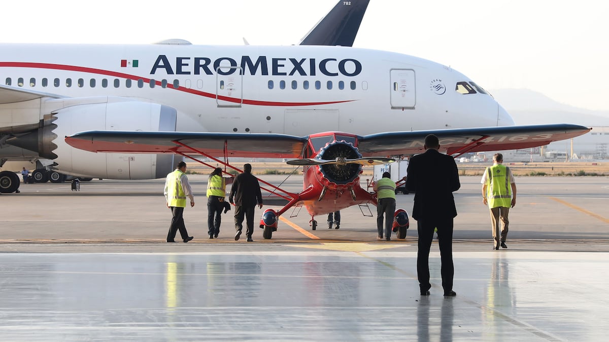 Empleados posan frente a un avión Stinson SR de Grupo Aeromexico SAB, restaurado, cerca de un Dreamliner de Boeing Co. en el Aeropuerto Internacional Benito Juárez de la Ciudad de México.