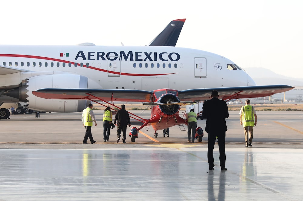Empleados posan frente a un avión Stinson SR de Grupo Aeromexico SAB, restaurado, cerca de un Dreamliner de Boeing Co. en el Aeropuerto Internacional Benito Juárez de la Ciudad de México. Empleados posan frente a un avión Stinson SR de Grupo Aeromexico SAB, restaurado, cerca de un Dreamliner de Boeing Co. en el Aeropuerto Internacional Benito Juárez de la Ciudad de México.