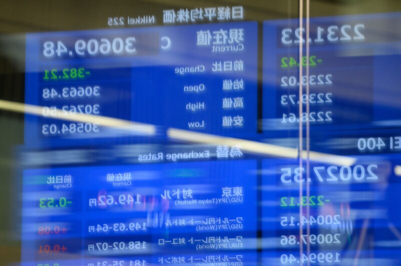 Um reflexo de uma tela exibindo a média de ações do Nikkei 225 Um reflexo de uma tela exibindo a média de ações do Nikkei 225