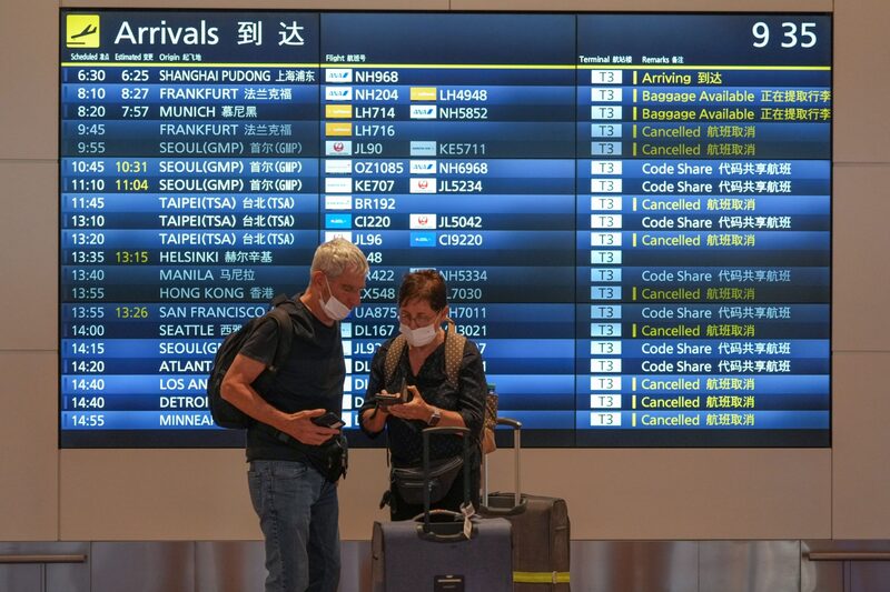 Pasajeros frente a un panel de información de vuelos en el aeropuerto de Haneda. Pasajeros frente a un panel de información de vuelos en el aeropuerto de Haneda.