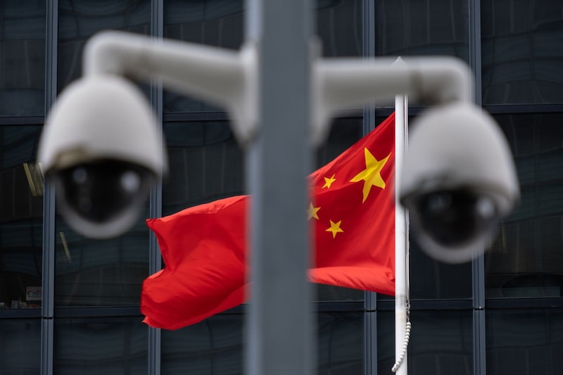 Las banderas de China ondean detrás de una cámara de vigilancia. Las banderas de China ondean detrás de una cámara de vigilancia.