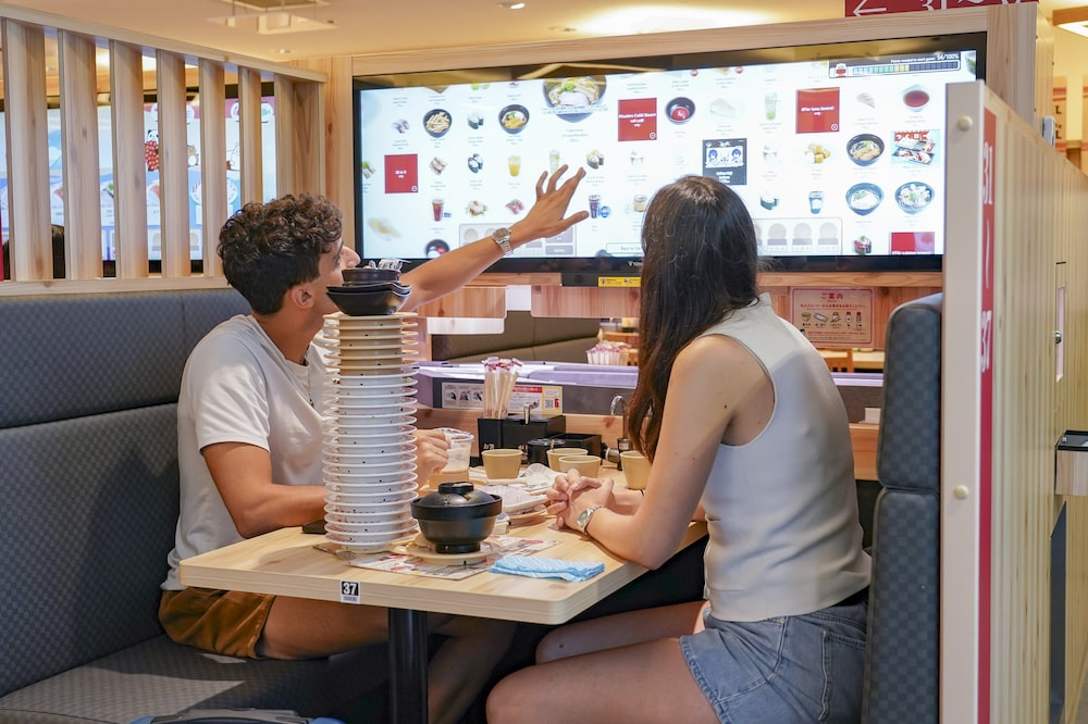 Tourists order sushi using an interactive touchscreen. Tourists order sushi using an interactive touchscreen.