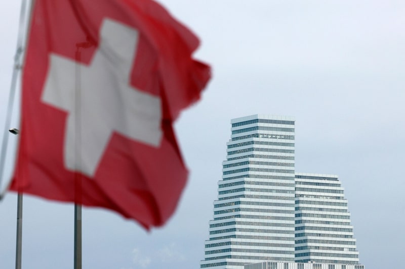 La Torre Roche en el campus de la sede central de Roche Holding AG, detrás de una bandera suiza en Basilea. La Torre Roche en el campus de la sede central de Roche Holding AG, detrás de una bandera suiza en Basilea.