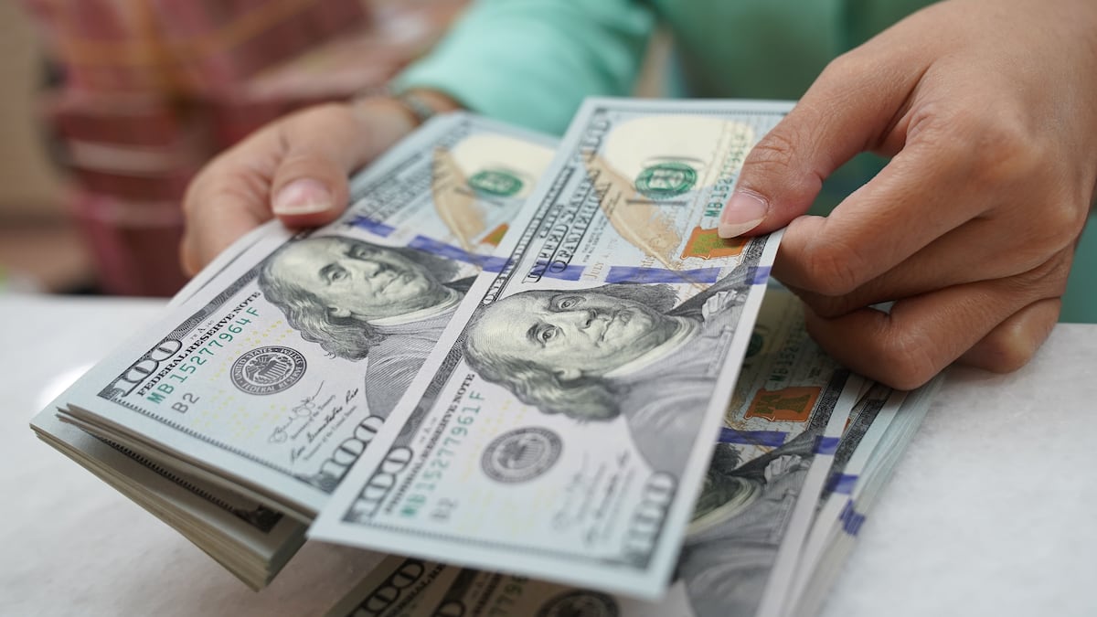 Una persona cuenta varios billetes de US$100.