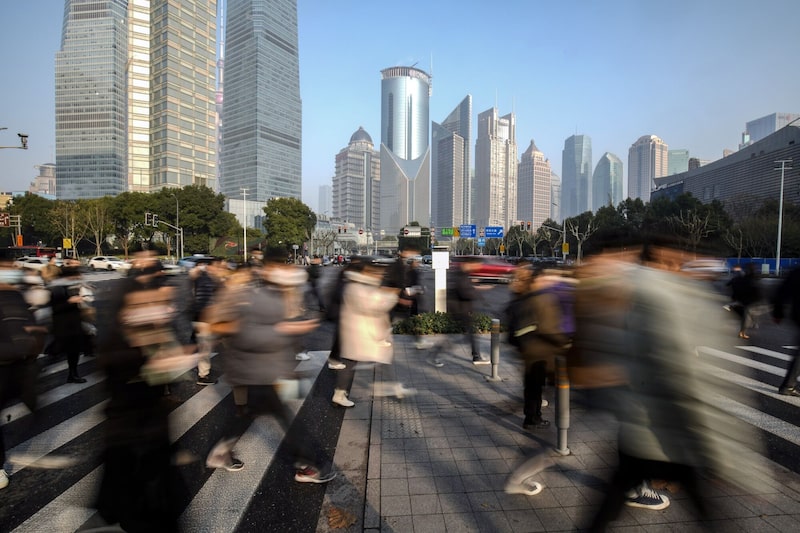 Pedestres cruzam a rua no distrito financeiro de Xangai, na China Pedestres cruzam a rua no distrito financeiro de Xangai, na China