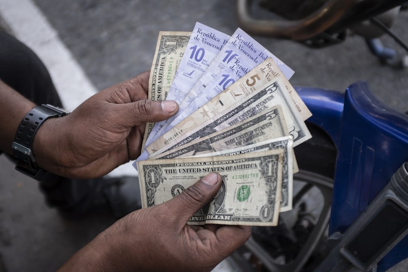 Un vendedor en el barrio de Petare, en Caracas, sostiene billetes de bolívares venezolanos y dólares estadounidenses. Un vendedor en el barrio de Petare, en Caracas, sostiene billetes de bolívares venezolanos y dólares estadounidenses.