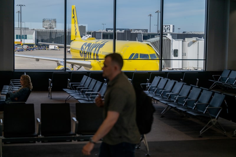 Pasajeros esperan en una sala de embarque mientras un avión de Spirit Airlines permanece estacionado en la puerta de un aeropuerto. Pasajeros esperan en una sala de embarque mientras un avión de Spirit Airlines permanece estacionado en la puerta de un aeropuerto.