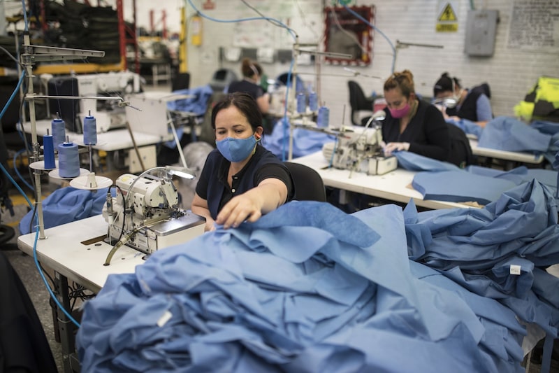Trabajadores cosen batas médicas protectoras en la fábrica de ropa de la Policía Nacional en Bogotá, Colombia, el sábado 28 de marzo de 2020. Trabajadores cosen batas médicas protectoras en la fábrica de ropa de la Policía Nacional en Bogotá, Colombia, el sábado 28 de marzo de 2020.