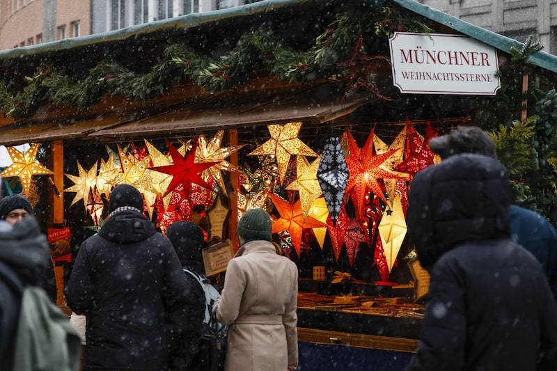 Compradores observan un puesto de luces festivas en el mercado navideño bajo la nieve en Múnich, Alemania, el viernes 9 de diciembre de 2022. Compradores observan un puesto de luces festivas en el mercado navideño bajo la nieve en Múnich, Alemania, el viernes 9 de diciembre de 2022.