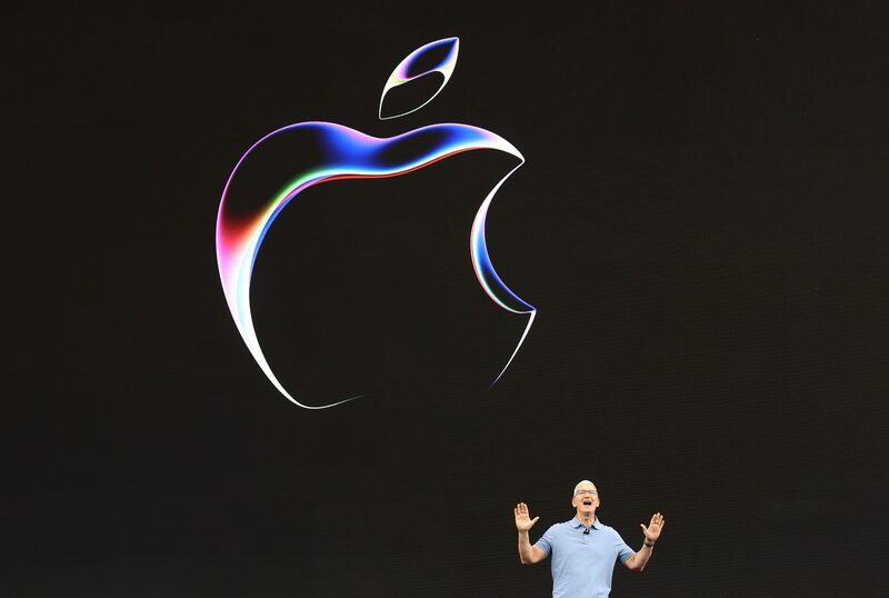 Homem gesticulando em frente ao logotipo da Apple Homem gesticulando em frente ao logotipo da Apple