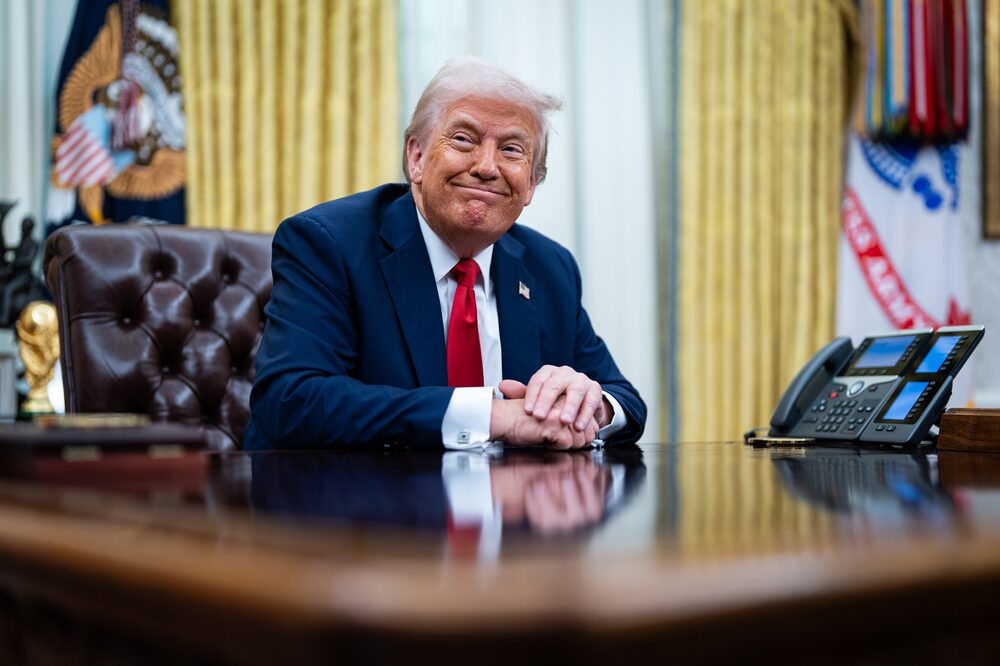 Donald Trump sentado à mesa no Salão Oval Donald Trump sentado à mesa no Salão Oval