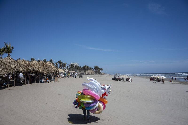 Uma pessoa percorrendo uma praia vazia com boias nos ombros Uma pessoa percorrendo uma praia vazia com boias nos ombros