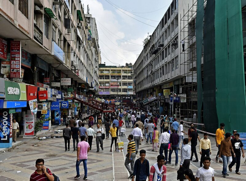 Pedestrians walk along a street in an electronics market in New Delhi, India Pedestrians walk along a street in an electronics market in New Delhi, India