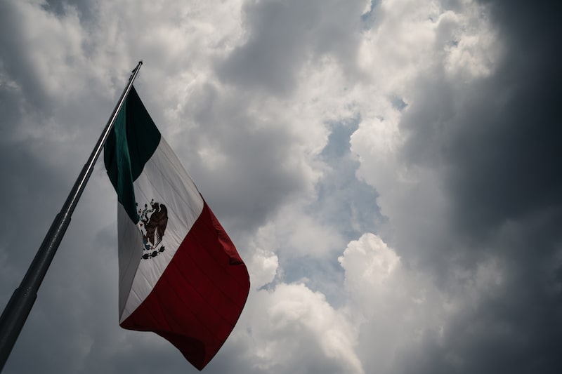 The Mexican flag in Zocalo Square before a storm in Mexico City, Mexico, on Monday, July 14, 2025. The Mexican peso slumped further Monday morning, leading losses among emerging-market currencies following Donald Trump's weekend threat to impose 30% tariffs on the country. Photographer: Mayolo Lopez Gutierrez/Bloomberg. The Mexican flag in Zocalo Square before a storm in Mexico City, Mexico, on Monday, July 14, 2025. The Mexican peso slumped further Monday morning, leading losses among emerging-market currencies following Donald Trump's weekend threat to impose 30% tariffs on the country. Photographer: Mayolo Lopez Gutierrez/Bloomberg.