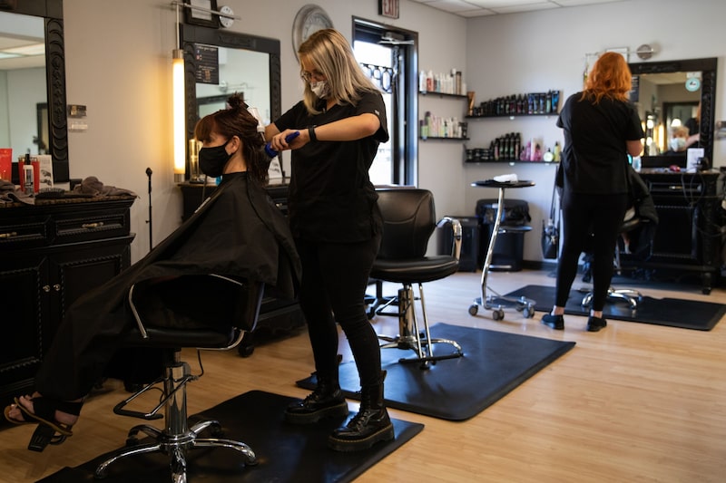 Una estilista seca el cabello de una clienta en un salón de bellez Una estilista seca el cabello de una clienta en un salón de bellez