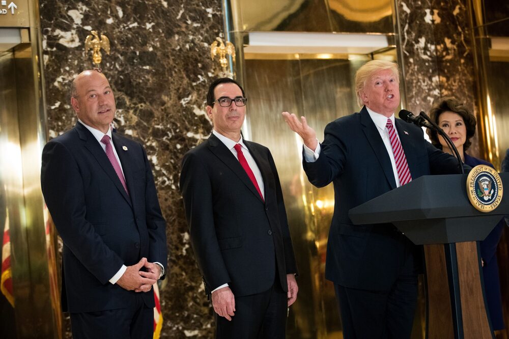 O então presidente Donald Trump com o diretor do conselho econômico nacional Gary Cohn e o secretário do Tesouro Steve Mnuchin em agosto de 2017: ex-executivos do Goldman Sachs em cargos-chave do governo em seu mandato O então presidente Donald Trump com o diretor do conselho econômico nacional Gary Cohn e o secretário do Tesouro Steve Mnuchin em agosto de 2017: ex-executivos do Goldman Sachs em cargos-chave do governo em seu mandato