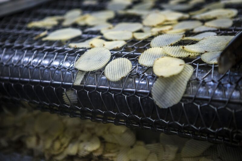 Las patatas cortadas se mueven a lo largo de una cinta transportadora hacia la máquina de freír. Las patatas cortadas se mueven a lo largo de una cinta transportadora hacia la máquina de freír.