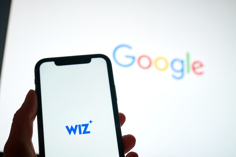 Letreiro da Google ao fundo. Em primeiro plano, um smartphone com o logotipo da Wiz Letreiro da Google ao fundo. Em primeiro plano, um smartphone com o logotipo da Wiz
