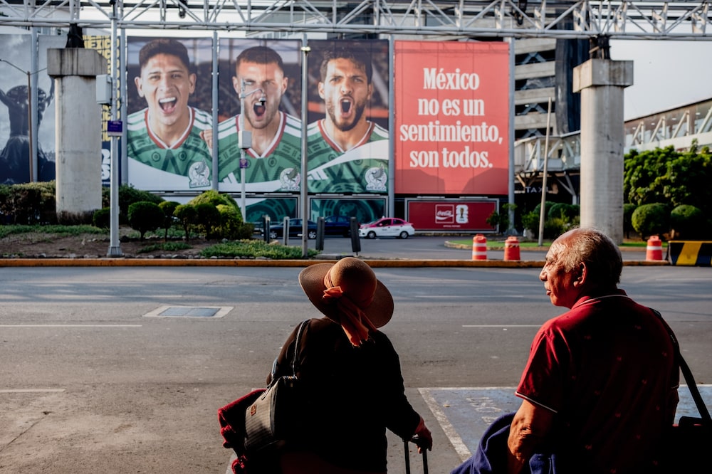 Turistas posam em frente a um outdoor que anuncia a seleção mexicana de futebol, no início do torneio, em 11 de junho (Foto: Fred Ramos/Bloomberg) Turistas posam em frente a um outdoor que anuncia a seleção mexicana de futebol, no início do torneio, em 11 de junho (Foto: Fred Ramos/Bloomberg)