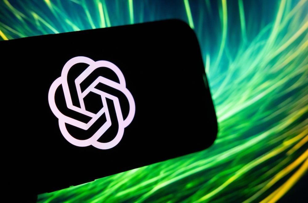 Logo de OpenAI en la pantalla de un teléfono móvil, sobre un fondo de luces verdes y azules. Logo de OpenAI en la pantalla de un teléfono móvil, sobre un fondo de luces verdes y azules.