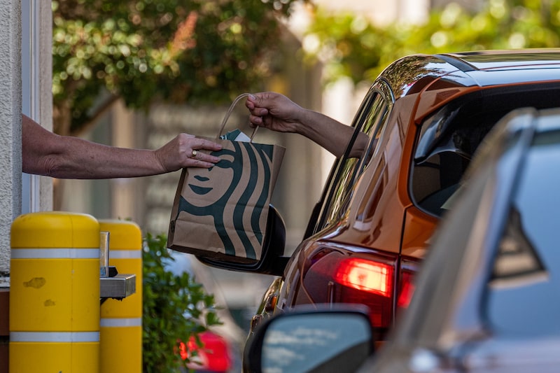 An employee hands a bag to a customer at a Starbucks coffee shop in California. An employee hands a bag to a customer at a Starbucks coffee shop in California.