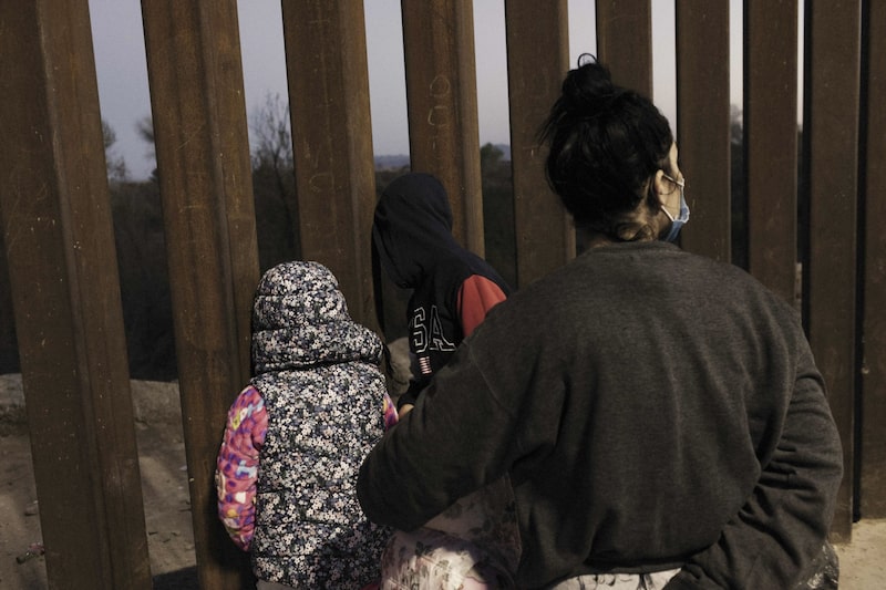 Niños migrantes en busca de asilo miran a través de una sección de la valla fronteriza entre México y Estados Unidos en Yuma, Arizona, Estados Unidos, el jueves 17 de febrero de 2022. Niños migrantes en busca de asilo miran a través de una sección de la valla fronteriza entre México y Estados Unidos en Yuma, Arizona, Estados Unidos, el jueves 17 de febrero de 2022.