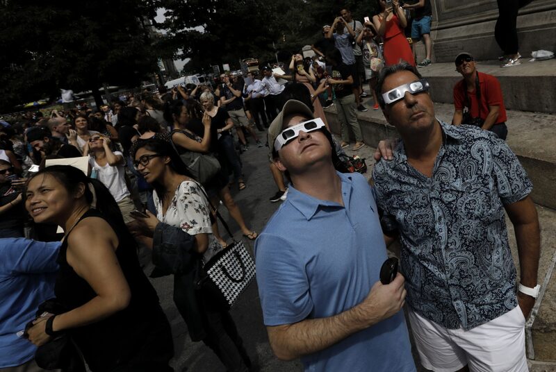 People wear solar viewing glasses while looking at the sun during a solar eclipse near Columbus Circle in New York, U.S., on Monday, Aug. 21, 2017. Millions of Americans across a 70-mile-wide (113-kilometer) corridor from Oregon to South Carolina will see the sky darken as the sun disappears from view total during the eclipse. Photographer: Peter Foley/Bloomberg People wear solar viewing glasses while looking at the sun during a solar eclipse near Columbus Circle in New York, U.S., on Monday, Aug. 21, 2017. Millions of Americans across a 70-mile-wide (113-kilometer) corridor from Oregon to South Carolina will see the sky darken as the sun disappears from view total during the eclipse. Photographer: Peter Foley/Bloomberg