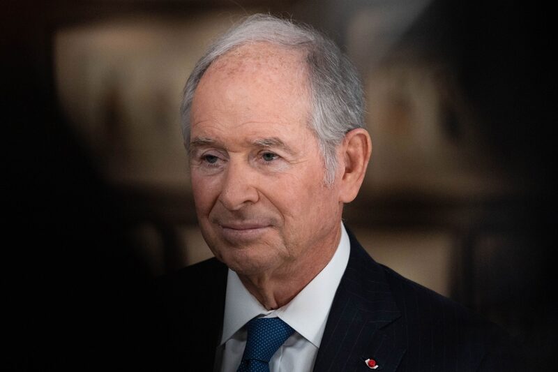 Foto do busto de Stephen Schwarzman, um homem grisalho usando terno preto, camisa branca e gravata azul escuro Foto do busto de Stephen Schwarzman, um homem grisalho usando terno preto, camisa branca e gravata azul escuro
