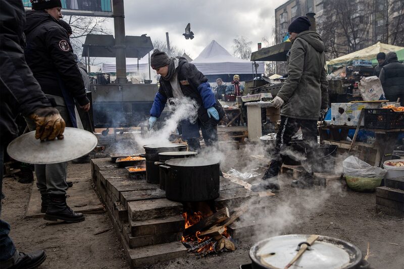 Voluntários fazem comida para alimentar soldados e civis em um acampamento à beira da estrada Voluntários fazem comida para alimentar soldados e civis em um acampamento à beira da estrada