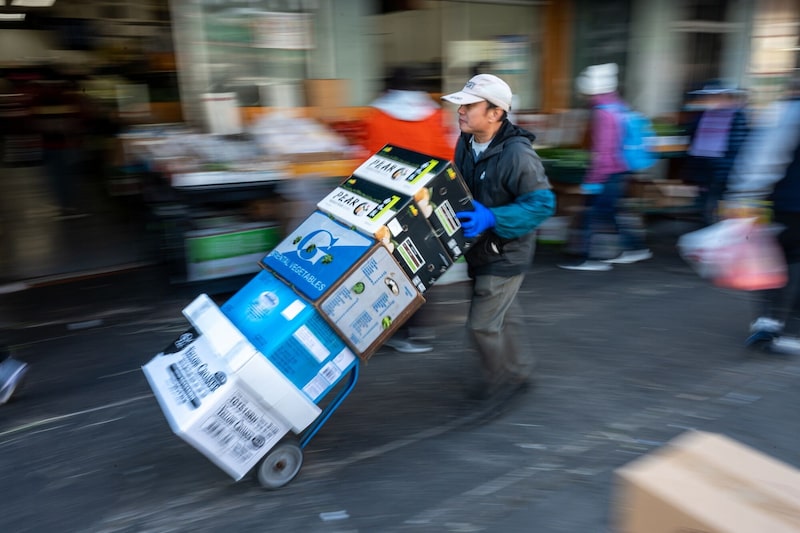 Un trabajador empuja una carretilla con productos agrícolas en el barrio chino de San Francisco. Un trabajador empuja una carretilla con productos agrícolas en el barrio chino de San Francisco.