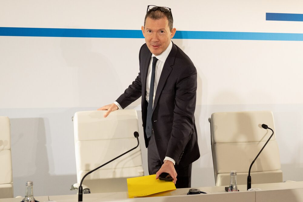 Homem vestindo camisa e terno e óculos na cabeça se prepara para sentar em uma mesa Homem vestindo camisa e terno e óculos na cabeça se prepara para sentar em uma mesa