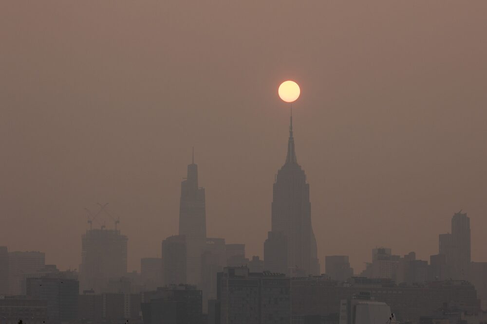Buildings in the Manhattan skyline shrouded in smoke from Canada wildfires at sunrise in Jersey City, New Jersey. Buildings in the Manhattan skyline shrouded in smoke from Canada wildfires at sunrise in Jersey City, New Jersey.