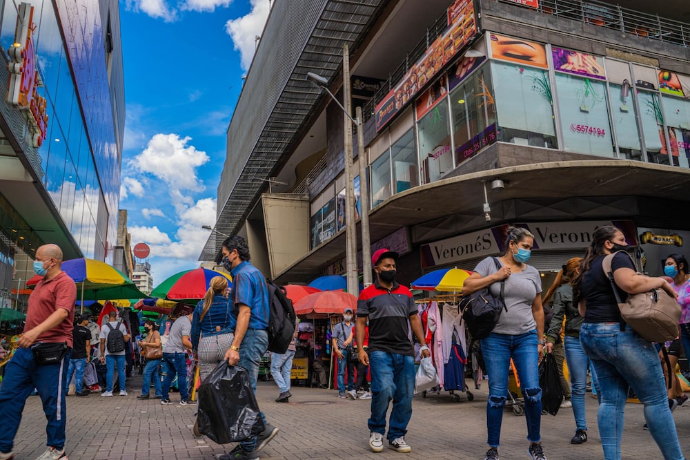 Peatones con mascarillas protectoras caminan junto a vendedores ambulantes en Medellín, Colombia, el jueves 20 de mayo de 2021 Peatones con mascarillas protectoras caminan junto a vendedores ambulantes en Medellín, Colombia, el jueves 20 de mayo de 2021