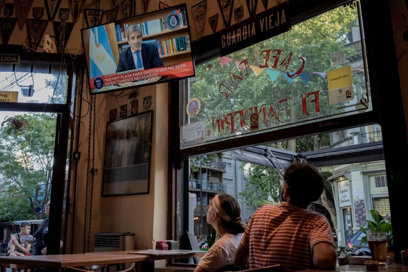 Customers watch a television as Luis Caputo, Argentina's economy minister, delivers a recorded speech on economic measures at a bar in Buenos Aires, Argentina, on Tuesday, Dec. 12, 2023. Argentina devalued the peso by 54% and announced a swath of spending cuts as the first steps of President Javier Milei's shock-therapy program to revive the nations troubled economy. Photographer: Anita Pouchard Serra/Bloomberg Customers watch a television as Luis Caputo, Argentina's economy minister, delivers a recorded speech on economic measures at a bar in Buenos Aires, Argentina, on Tuesday, Dec. 12, 2023. Argentina devalued the peso by 54% and announced a swath of spending cuts as the first steps of President Javier Milei's shock-therapy program to revive the nations troubled economy. Photographer: Anita Pouchard Serra/Bloomberg