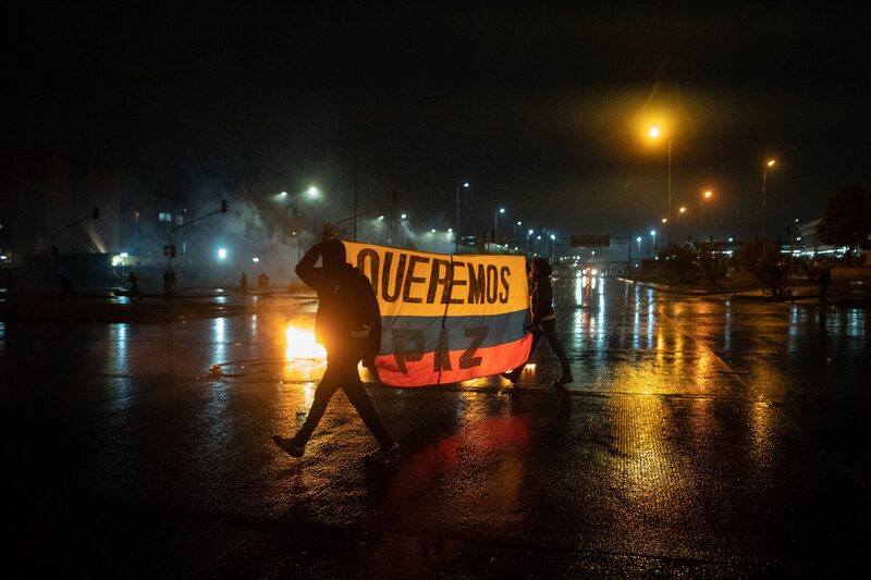 Los manifestantes sostienen una bandera colombiana que dice "queremos la paz" durante una protesta en Bogotá, Colombia, el viernes 28 de mayo de 2021. Los manifestantes sostienen una bandera colombiana que dice "queremos la paz" durante una protesta en Bogotá, Colombia, el viernes 28 de mayo de 2021.