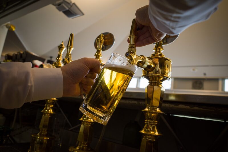 Imagem tirada de um ângulo mais baixo mostrando uma caneca de cerveja sendo preenchida em uma torneira Imagem tirada de um ângulo mais baixo mostrando uma caneca de cerveja sendo preenchida em uma torneira