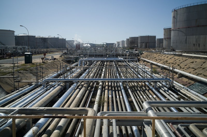 Tuberías cerca de los tanques de almacenamiento de combustible y petróleo crudo en la refinería Galp Energia SGPS SA Sines, en Sines, Portugal. Tuberías cerca de los tanques de almacenamiento de combustible y petróleo crudo en la refinería Galp Energia SGPS SA Sines, en Sines, Portugal.