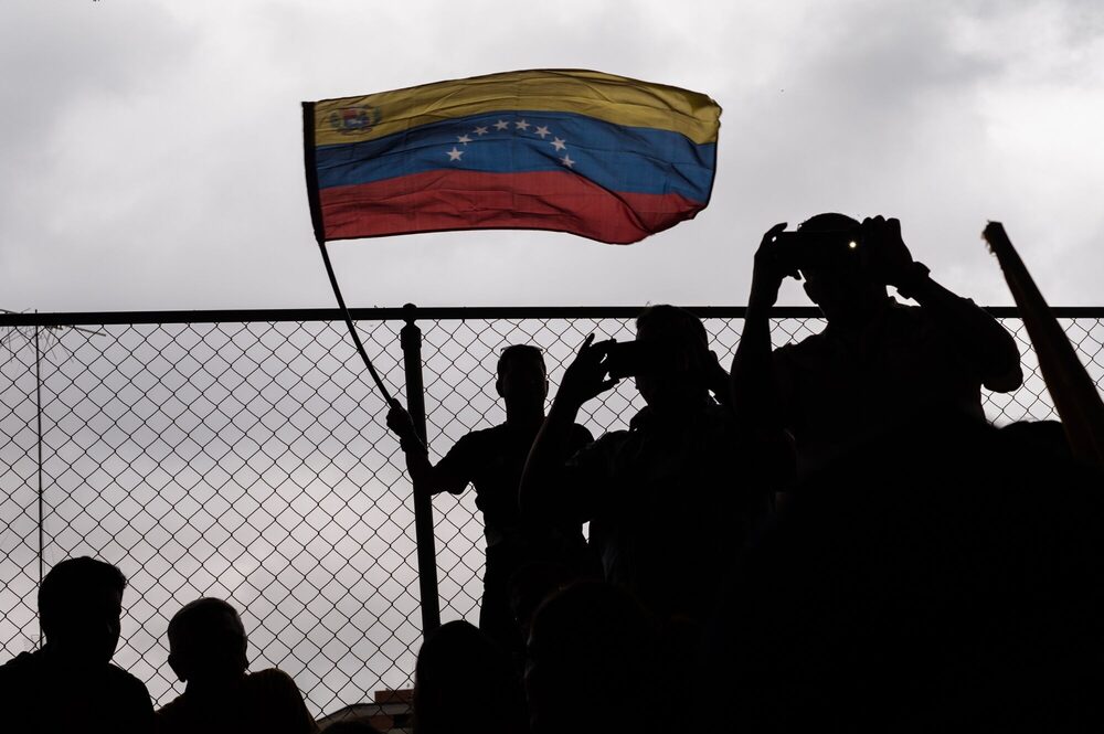 Unos hombres ondean la bandera de Venezuela. Unos hombres ondean la bandera de Venezuela.