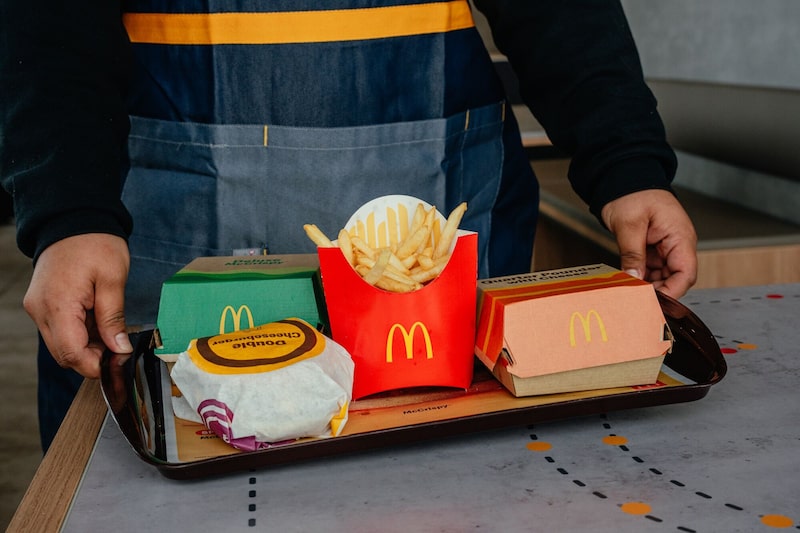 Un empleado lleva una bandeja con comida a un cliente en un restaurante McDonald's de Zion, Illinois. Un empleado lleva una bandeja con comida a un cliente en un restaurante McDonald's de Zion, Illinois.