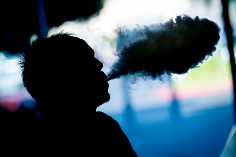 Un cliente exhala una nube de vapor de un cigarrillo electrónico. Un cliente exhala una nube de vapor de un cigarrillo electrónico.