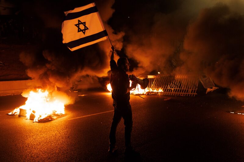 Un manifestante en la capital de Tel Aviv ondea una bandera de Israel en un camino bloqueado en la autopista Ayalon durante una protesta contra la coalición del Gobierno del primer ministro Benjamin Netanyahu y sus reformas judiciales (Foto: Kobi Wolf/Bloomberg) Un manifestante en la capital de Tel Aviv ondea una bandera de Israel en un camino bloqueado en la autopista Ayalon durante una protesta contra la coalición del Gobierno del primer ministro Benjamin Netanyahu y sus reformas judiciales (Foto: Kobi Wolf/Bloomberg)