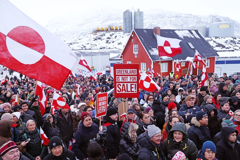 La gente sostiene banderas y pancartas de Groenlandia mientras se reúne frente al consulado de Estados Unidos para marchar en protesta contra el presidente estadounidense Donald Trump. La gente sostiene banderas y pancartas de Groenlandia mientras se reúne frente al consulado de Estados Unidos para marchar en protesta contra el presidente estadounidense Donald Trump.