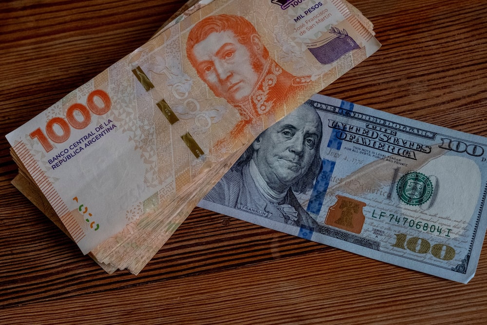 Billetes de pesos argentinos junto a billetes de US$100 en Buenos Aires. Billetes de pesos argentinos junto a billetes de US$100 en Buenos Aires.
