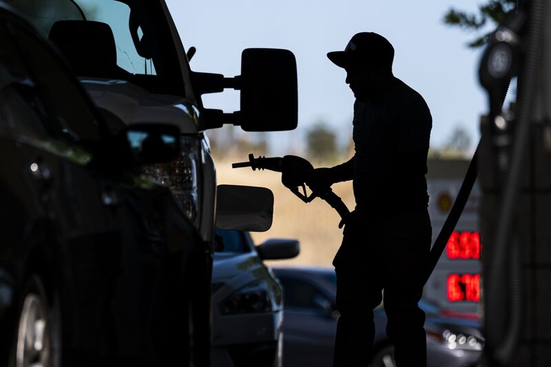 Un cliente de una gasolinera inserta la manguera de una bomba para cargar combustible. Un cliente de una gasolinera inserta la manguera de una bomba para cargar combustible.