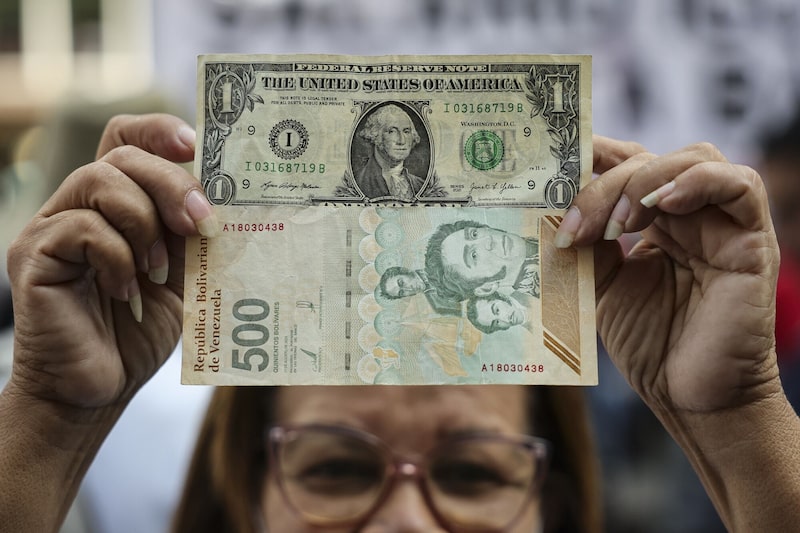 Una mujer sostiene un billete de 1 dólar estadounidense y otro de 500 bolívares durante una manifestación a favor de un aumento salarial en Caracas, el 26 de febrero. Una mujer sostiene un billete de 1 dólar estadounidense y otro de 500 bolívares durante una manifestación a favor de un aumento salarial en Caracas, el 26 de febrero.
