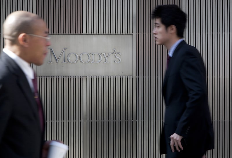 Letrero fuera de Moody´s con transeúntes Letrero fuera de Moody´s con transeúntes